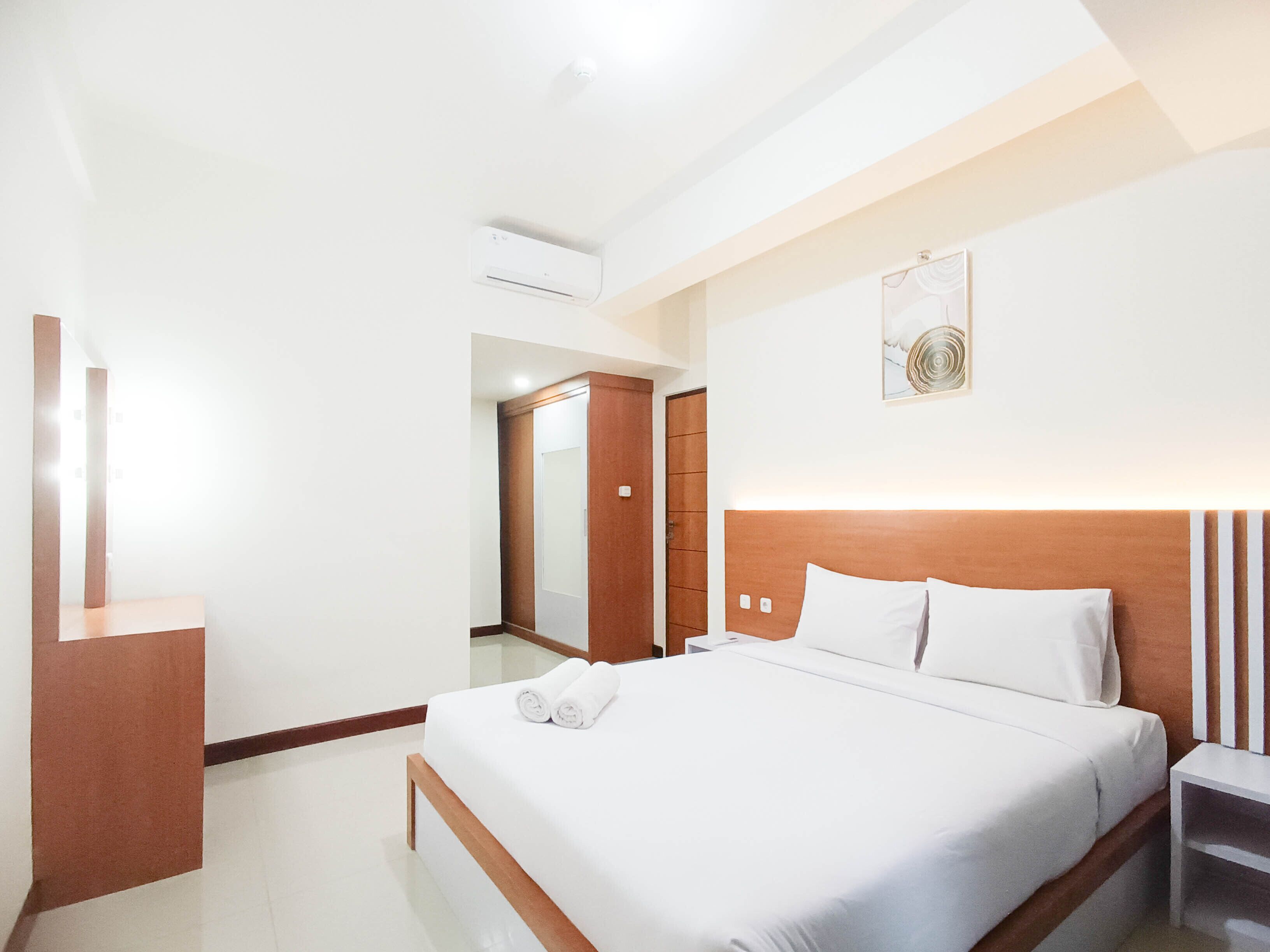 Een hotelkamer met een groot bed, een nachtkastje, een spiegel en een wandairconditioning.