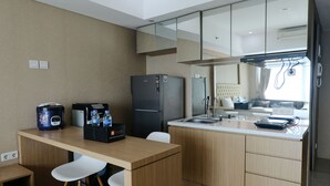 A compact kitchen with a refrigerator, a coffee maker, and a sink. - Good Choice Studio Apartment At Tamansari La Grande (Bandung)