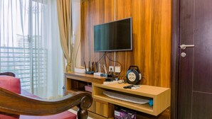 Een kamer met een houten tv aan de muur, een bureau met een computer en een rode stoel.