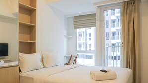 Ein Hotelzimmer mit einem großen Bett, einem Fernseher auf einem Tisch, einem Holzschrank und einem Fenster mit Blick auf ein Gebäude.
