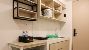 Eine kompakte Küche mit Arbeitsplatte, Spüle und Holzschränken. Auf der Arbeitsplatte stehen zwei Wasserflaschen und eine schwarze Tasche mit dem Aufdruck 'travelio'.