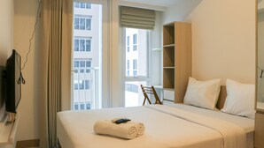A hotel room with a bed, a TV, a window with curtains, and a wooden shelf. - Stylish Studio At Tokyo Riverside Pik 2 Apartment (Teluknaga)