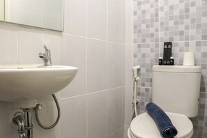 A bathroom with a white sink, a toilet, and a shower. There are toiletries on the toilet tank. - Stylish Studio At Tokyo Riverside Pik 2 Apartment (Teluknaga)