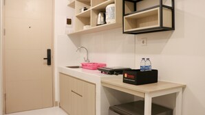 A compact kitchen with a sink, a countertop, and a black box labeled "Travelio" on a small table. - Stylish Studio At Tokyo Riverside Pik 2 Apartment (Teluknaga)
