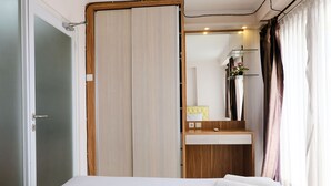 Ein Hotelzimmer mit Bett, Nachttisch aus Holz, Spiegel, Badezimmer mit Waschbecken und Duschbereich.