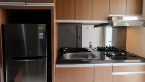 A kitchen with a stainless steel refrigerator, a double sink, and a gas stove.