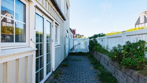 A narrow cobblestone pathway between buildings with white railings and a brick wall on one side. - 4 Person Holiday Home in Ringkobing (Ringkobing)
