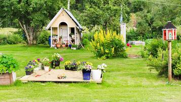 A small wooden structure with a pitched roof, surrounded by a variety of potted plants and flowers.