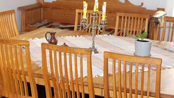 A wooden dining table with a patterned tablecloth, surrounded by wooden chairs.