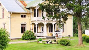 A two-story building with a porch, a chimney, and a well-maintained lawn.