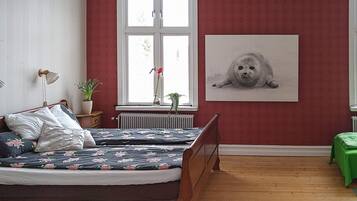 A bedroom with a bed, a radiator, a window, and a framed picture on the wall.