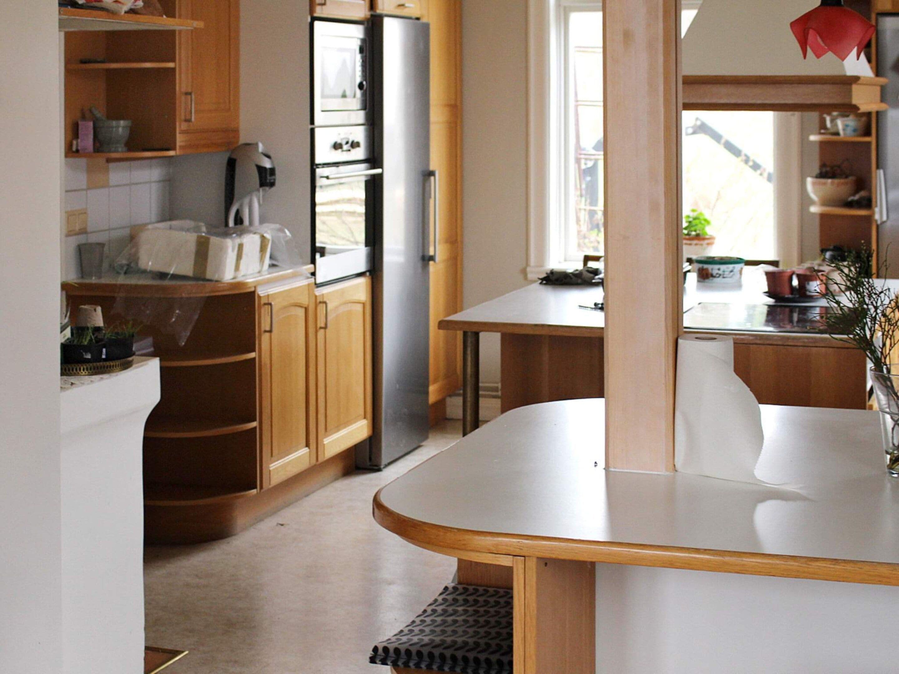 A kitchen with wooden cabinets, a stainless steel refrigerator, a microwave, and a dining area with a table and chairs.