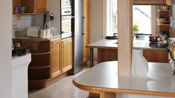 A kitchen with wooden cabinets, a stainless steel refrigerator, a microwave, and a dining area with a table and chairs.