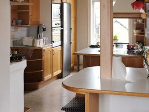 A kitchen with wooden cabinets, a stainless steel refrigerator, a microwave, and a dining area with a table and chairs.