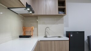 A modern kitchen with a built-in sink, wooden cabinets, and a black refrigerator. - Comfort 2Br At Daan Mogot City Apartment (Jakarta)