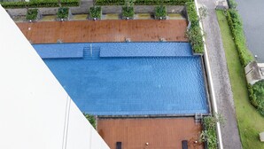 An aerial view of a rooftop pool with a wooden deck and a blue pool area. - Comfort 2Br At Daan Mogot City Apartment (Jakarta)