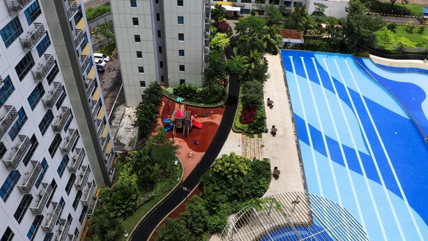 A high-rise building with multiple balconies, a swimming pool with blue lanes, and a playground area. - Full Furnished With Simply Look Studio At Springlake Summarecon Bekasi Apartment (Bekasi)