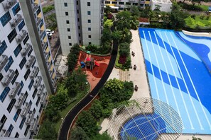 A high-rise building with multiple balconies, a swimming pool with blue lanes, and a playground area. - Full Furnished With Simply Look Studio At Springlake Summarecon Bekasi Apartment (Bekasi)