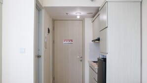 A narrow hallway with a wooden door, a phone, and a light switch on the wall. - Full Furnished With Simply Look Studio At Springlake Summarecon Bekasi Apartment (Bekasi)
