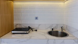 A kitchen with white marble tiles, a stainless steel sink, and a built-in oven. - Best Deal Studio Room With Private Jaccuzi At Art Deco Apartment (Bandung)