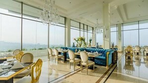 A spacious dining area with a blue sofa, gold chairs, and a chandelier. - Best Deal Studio Room With Private Jaccuzi At Art Deco Apartment (Bandung)