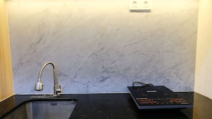 Une cuisine dotée d’un plan de travail noir, d’un évier en acier inoxydable et d’une plaque de cuisson à induction noire.