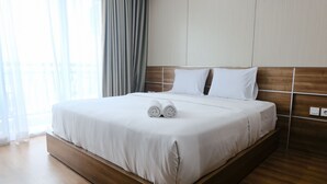 Una habitación de hotel moderna con una cama grande, cabecera de madera y vistas al exterior a través de cortinas translúcidas.