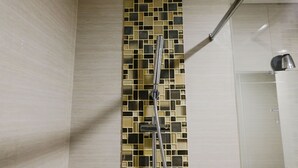 Ducha con pared de azulejos y cabezal de ducha de mano.