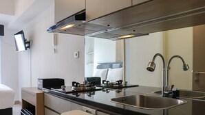 A modern kitchen with a stainless steel sink, a built-in stove, and a large mirror above the countertop. - Best Choice And Cozy Studio Apartment At Tokyo Riverside Pik 2 (Teluknaga)