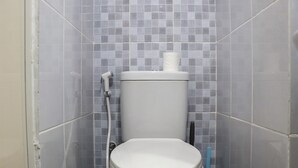 A bathroom with a toilet, a shower, and a tiled wall. - Best Choice And Cozy Studio Apartment At Tokyo Riverside Pik 2 (Teluknaga)