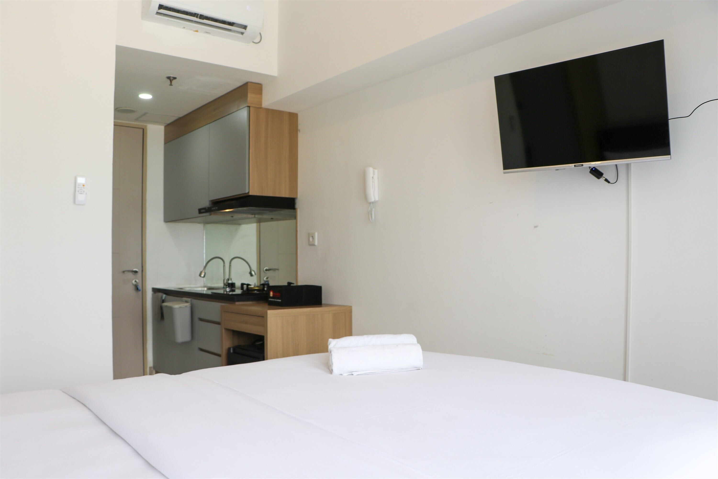 Quarto de hotel com cama, televisão na parede, pia e espelho.