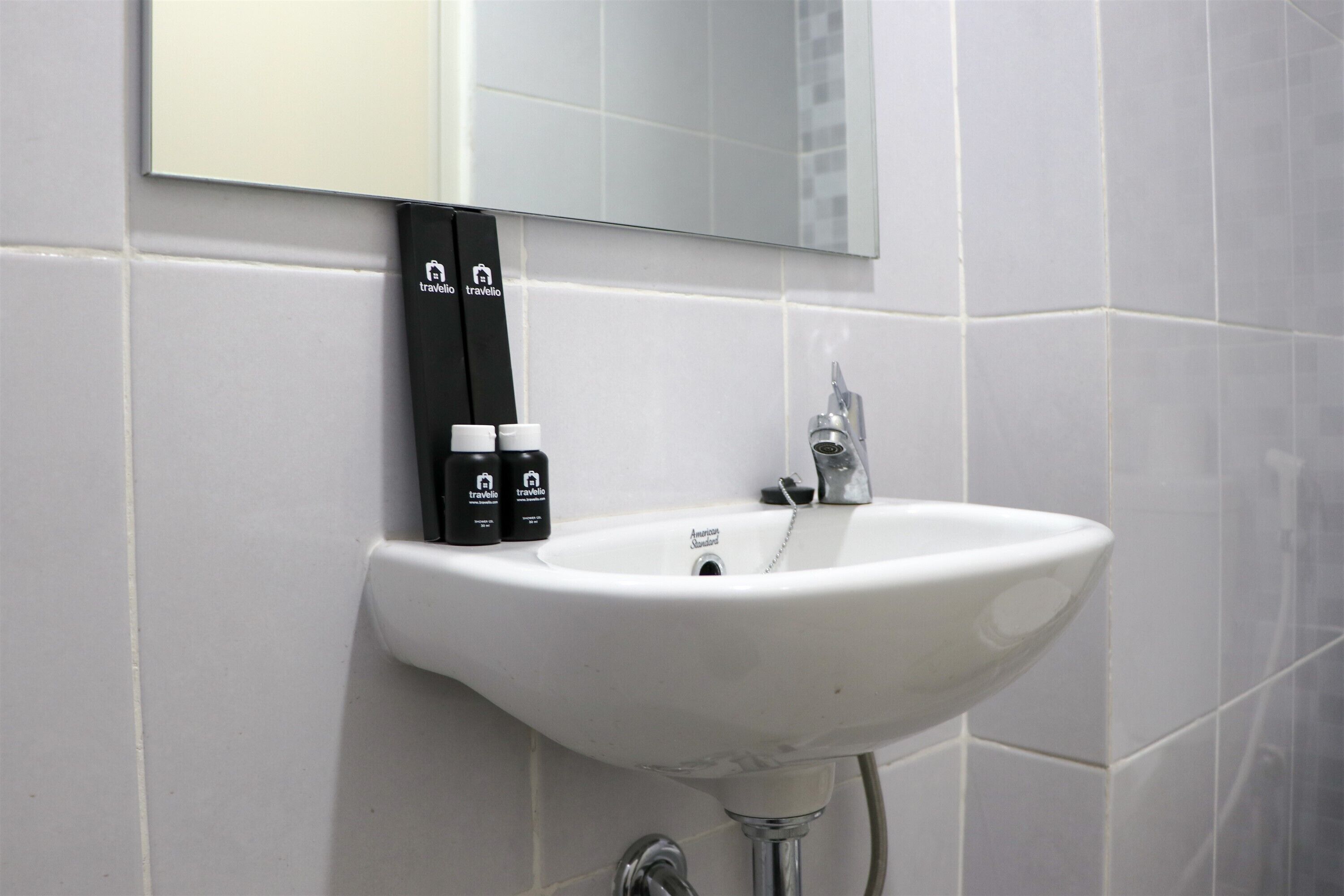 A white bathroom sink with a mirror above it and toiletries on the wall.