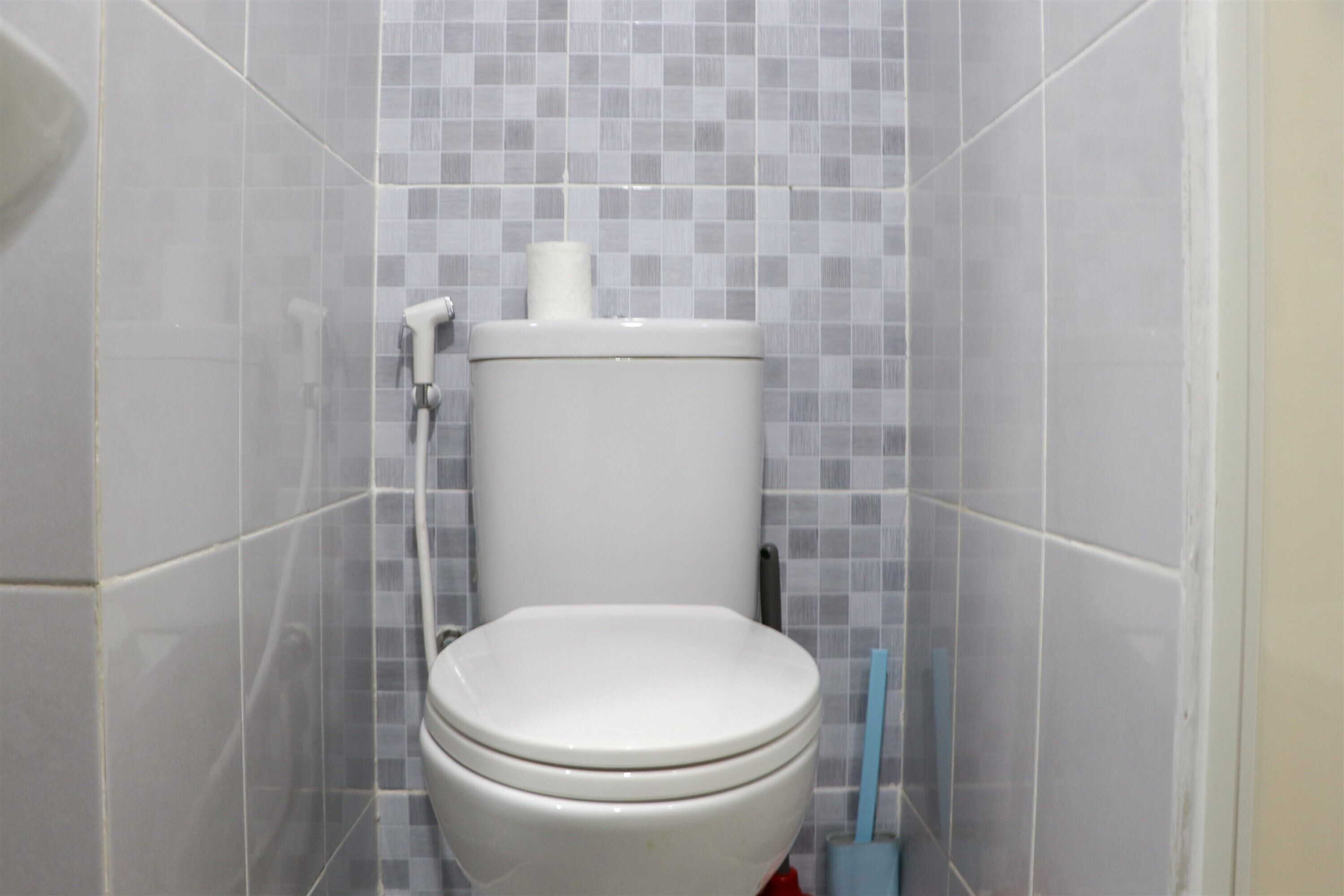 A bathroom with a toilet, a toilet paper holder, and a hand dryer.