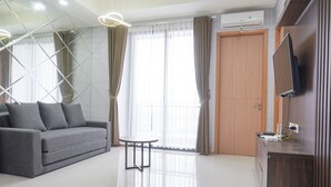 A modern living room with a grey sofa, a small round table, and a TV mounted on a wooden cabinet.