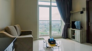 A modern living room with a sofa, a television on a stand, a small cabinet, and a window with curtains. - Modern Look 1Br At 22Nd Floor Ciputra International Apartment (Jakarta)