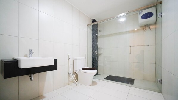 Un baño moderno con ducha de mampara de vidrio, lavabo blanco y retrete.
