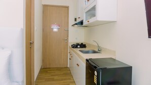 A compact kitchen with a wooden door, a sink, a stove, and a refrigerator. - Good Deal And Simply Look Studio Apartment At B Residence (Pagedangan)