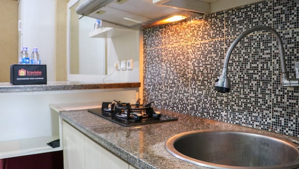 A kitchen with a stainless steel sink, a gas stove, and a tiled backsplash. - Fancy And Nice 2Br Apartment At Green Pramuka City (Jakarta)