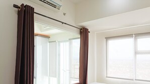 A hotel room with a bed, a window, and curtains. - Comfort 1Br At Vida View Makassar Apartment (Makassar)