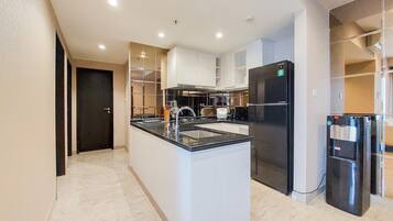 Una cocina moderna con una isla central, electrodomésticos integrados y suelo de mármol.