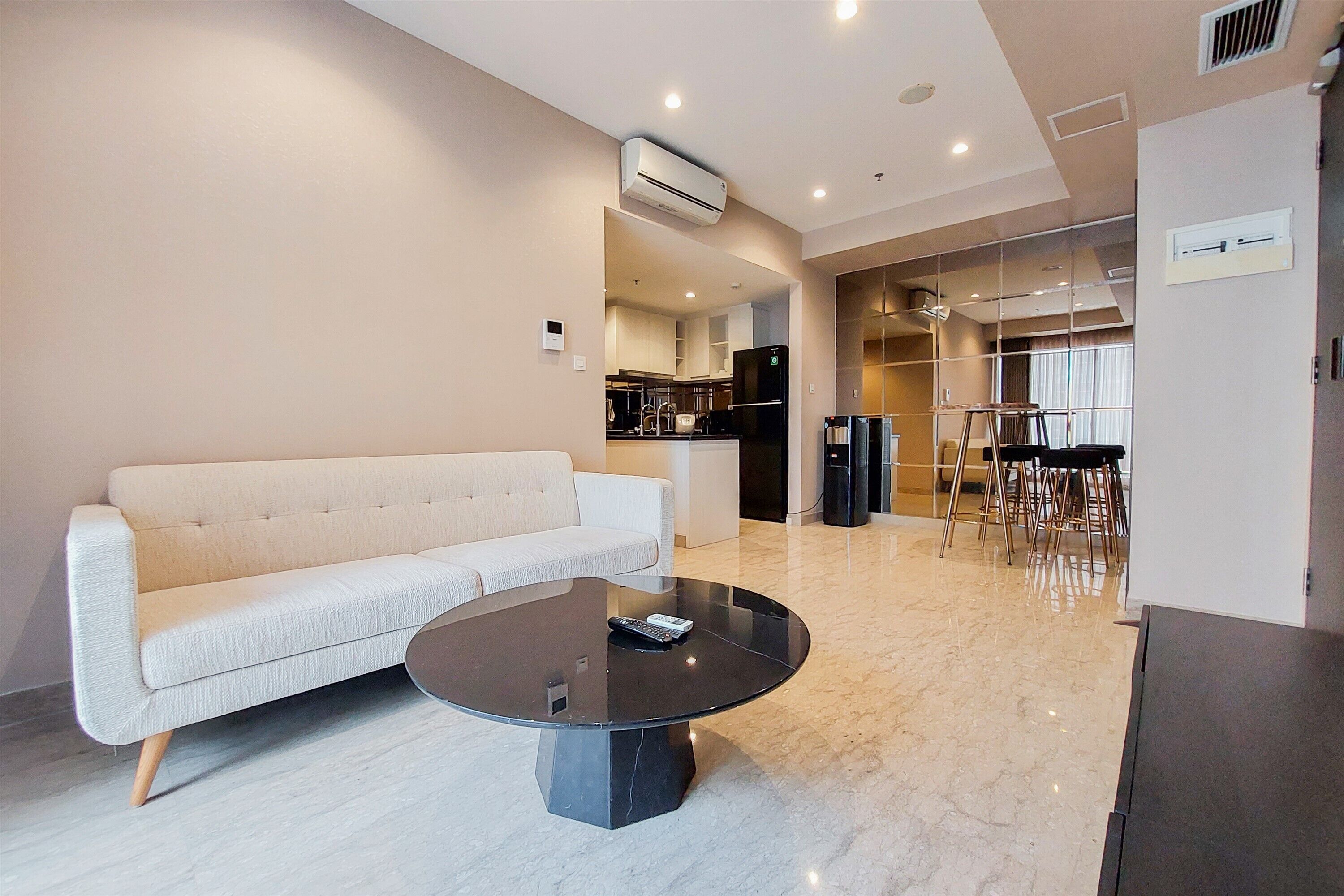 Una sala de estar moderna con un sofá, una mesa de centro y una cocina al fondo.