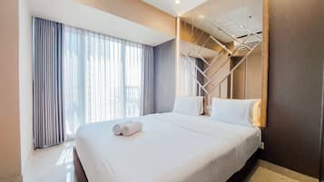 A hotel room with a large bed, a built-in wardrobe, and a view of the city through the window.