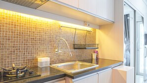 A modern kitchen with a stainless steel sink, a gas stove, and a tiled backsplash. - Strategic And Well Designed Studio Apartment At Capitol Park Residence (Jakarta)