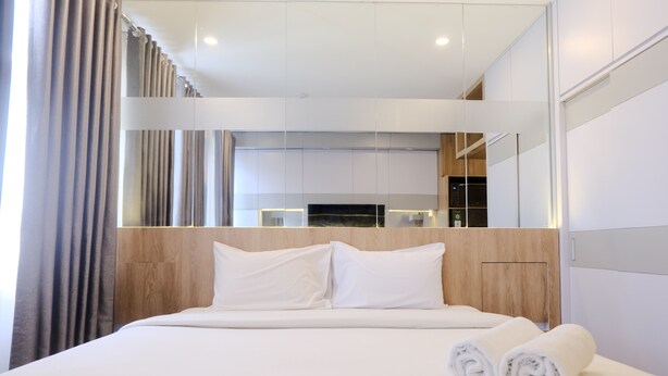 Ein modernes Hotelzimmer mit einem großen Bett, strahlend weißen Leinentüchern und einem ordentlich bezogenen Bett mit aufgerollten Handtüchern.