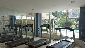 Une salle de sport équipée de tapis de course, d’un vélo d’appartement et d’un appareil d’aviron.