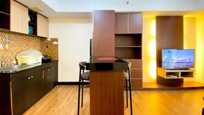 Cocina moderna con armarios de madera y un comedor con mesa y sillas. Un televisor de pantalla plana está montado en la pared.