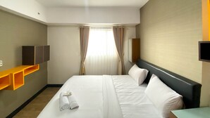 Habitación de hotel con cama, televisión, espejo y ventana con cortinas.