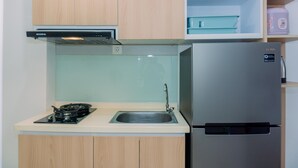 Una cocina compacta con muebles de madera, un refrigerador de acero inoxidable, una estufa a gas y un lavamanos.