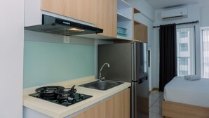 Una kitchenette compacta con estufa a gas, pileta y refrigerador de acero inoxidable.