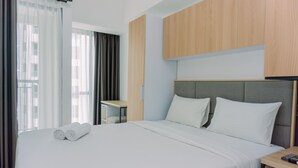Una habitación de hotel moderna con una cama grande, cabecero de madera, una mesita de noche pequeña y una ventana con cortinas.